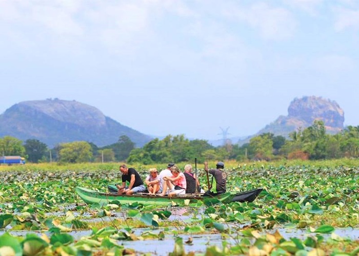 Traditional boat ride during Sigiriya village tour on a scenic lake surrounded by greenery