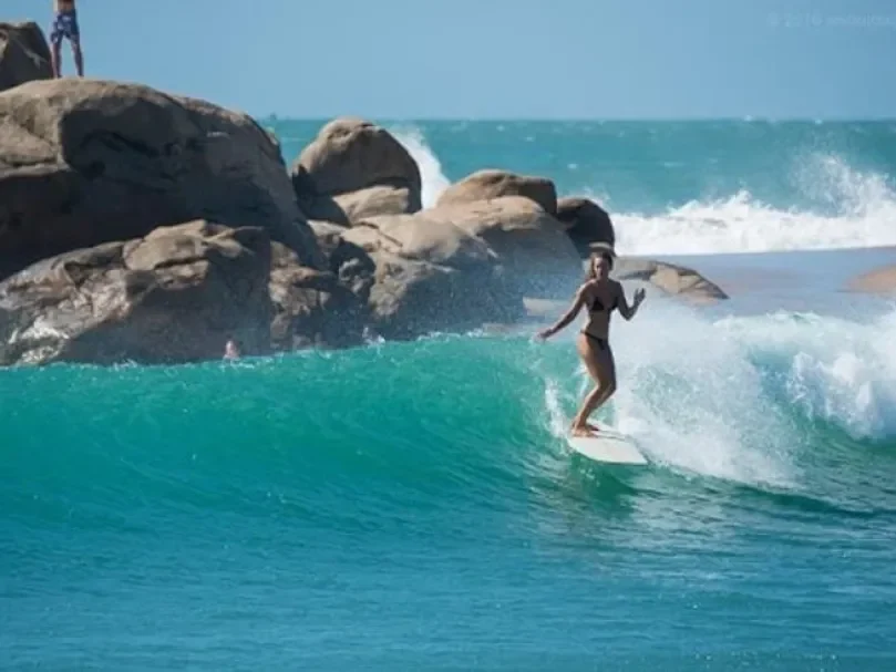 Girl surfing in Arugam Bay Sri Lanka with clear blue ocean waves