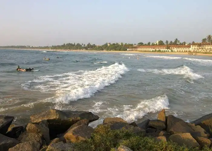Golden sandy Bentota Beach in Sri Lanka with calm waves and sunset sky