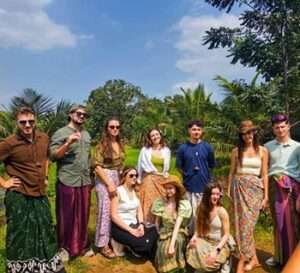 Tourists wearing traditional Sri Lankan clothes interacting with a local family during a village walk in Sigiriya