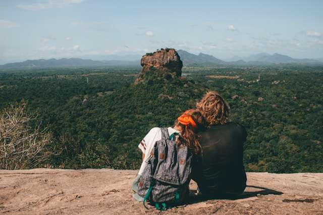 Couple sitting on Pidurangala Rock overlooking Sigiriya Lion Rock in Sri Lanka